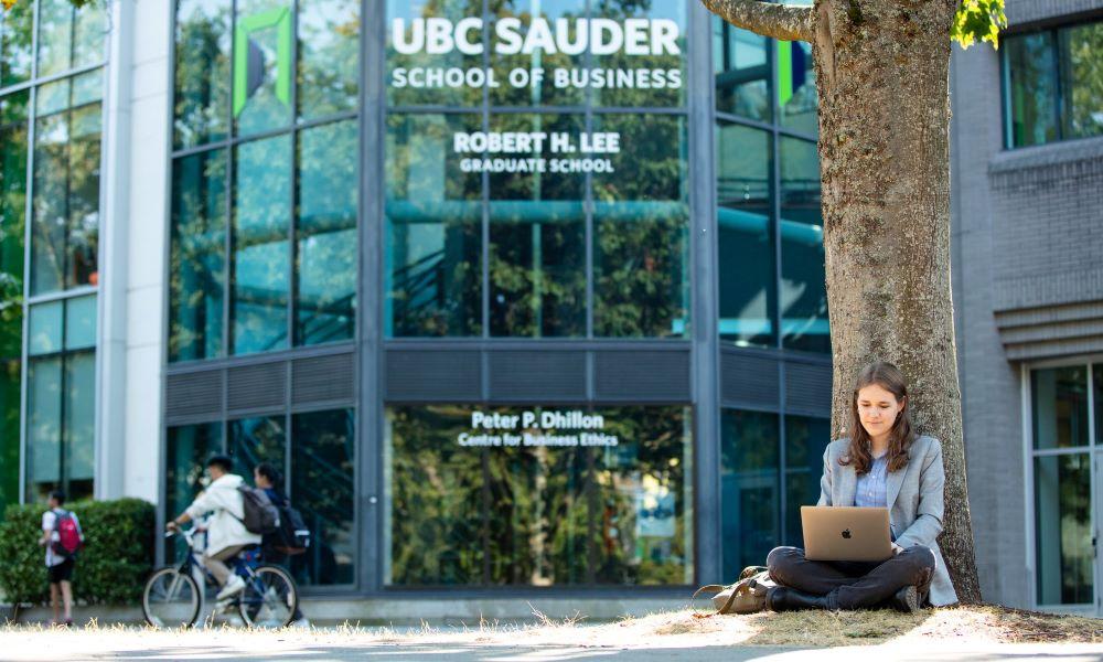 Student outside UBC Sauder on laptop